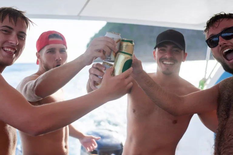 Они наслаждаются отдыхом. Портрет группы парней, пьющих пиво на яхте в море.